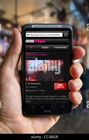 Watching the News Channel on BBC iPlayer on an HTC smartphone via a public Wi-Fi hotspot Stock Photo