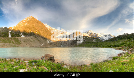 Swiss alpine mountain lake with meadow, a glacier and near Susten pass in summer at sunset, Switzerland Stock Photo
