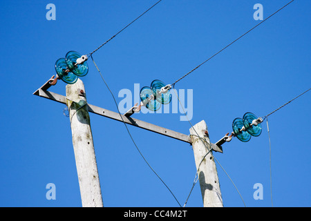 Electricity Poles with Wires and Green Glass Insulators against Deep Blue Sky Stock Photo