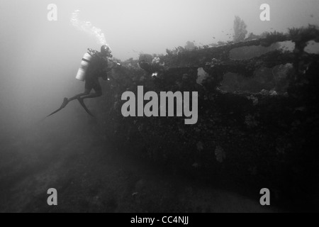 Scuba diver exploring the wreck of a 100 foot Japanese submarine chaser Stock Photo