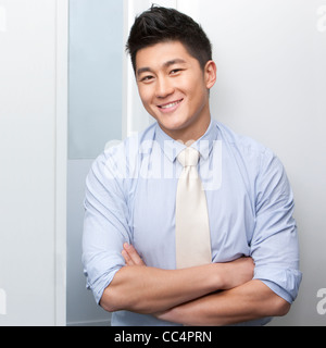 Smiling businessman with his arms crossed and colleagues in the background Stock Photo