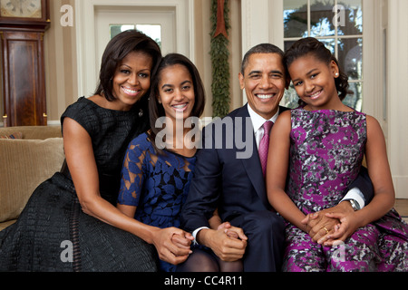 President Barack Obama, First Lady Michelle Obama, and daughters, Sasha and Malia, sit for a family portrait in the Oval Office Stock Photo