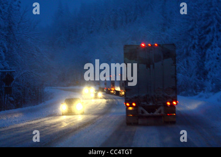40,524.02085 winter 18 wheelers trucks cars night snow storm slick snow covered 2-lane rural mountain road chains snowing lights on dangerous travel Stock Photo