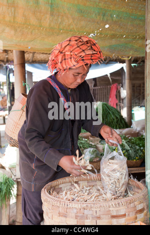 Woman is buying home-made dry fish on the street market. Pindaya, Burma. Stock Photo