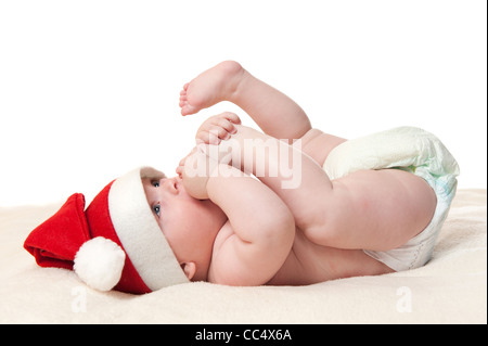 cute six month old baby boy in christmas hat playing with his feet, isolated on white background Stock Photo