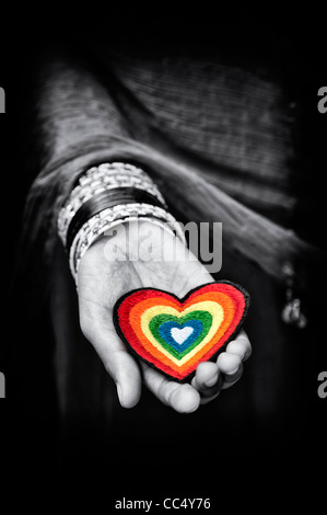 Indian girls hands holding an embroidery iron on patch of a multicoloured love heart. Black and white and Spot coloured. India Stock Photo