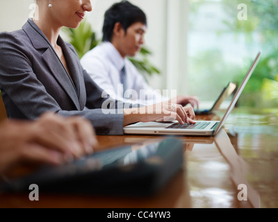 Group of businesspeople meeting in conference room and using laptop computers. Side view, copy space Stock Photo