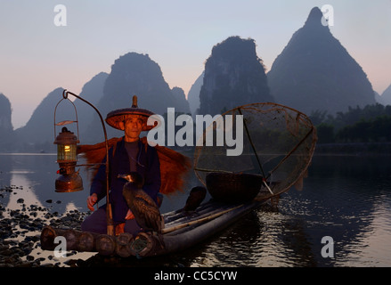Cormorant fisherman on bamboo raft with birds at dawn with lantern on the shore of the Li river Yangshuo Peoples Republic of China Stock Photo