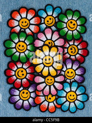 Embroidery iron on patches of Multicoloured smiley face flowers on a denim jean background Stock Photo