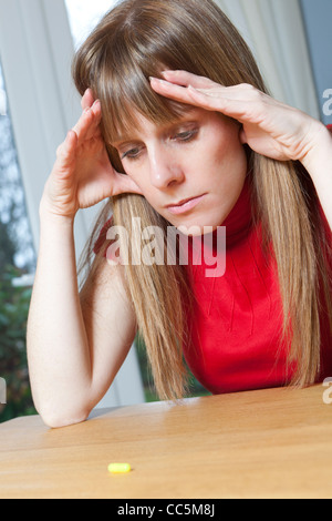 Woman with tablet. Deciding whether to take tablet. Stock Photo