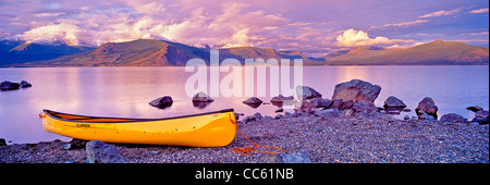 Yellow canoe on the shore of Kluane Lake at sunset with snow capped mountains in the background, Kluane National Park and reserv Stock Photo