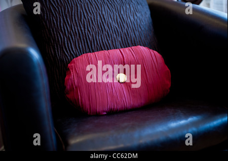 Bright red cushion in a leather arm chair Stock Photo