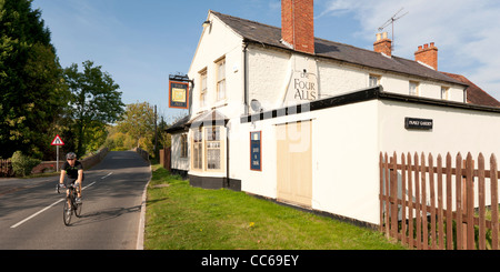 A cyclist passing the Four Alls pub in Welford-on-Avon, Warwickshire, England, UK Stock Photo