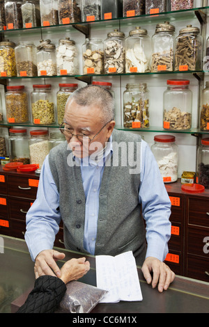 China, Hong Kong, Sheung Wan, Chinese Medicine Shop, Doctor Taking Pulse of Patient Stock Photo