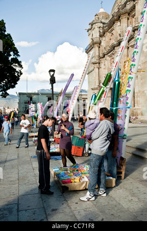 Mexican Downs Syndrome teenage boy with pretty smiling older sister selects torpedo balloon from vendor outside Oaxaca Cathedral Stock Photo