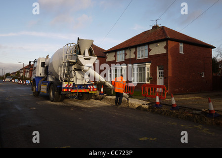 A workman pouring concrete on a residential street. Stock Photo