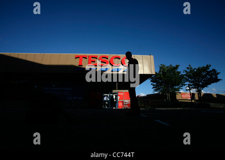 A youth seen in silhouette against the background of a Tesco supermarket Stock Photo