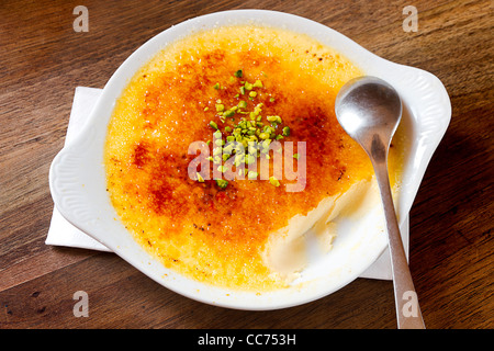 delicious large portion of creme brulee in a ceramic dish on rustic table with spoon Stock Photo