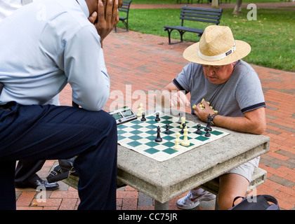 Men playing chess in an outdoor park table - USA Stock Photo