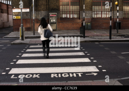 a female walks across a zebra crossing in London Stock Photo