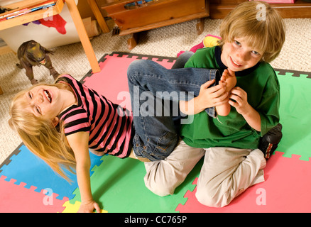 Twins wrestling and tickling in their playroom Stock Photo