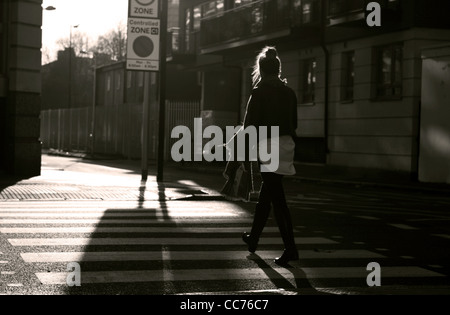 a female walks across a zebra crossing in London, photographed in sepia Stock Photo