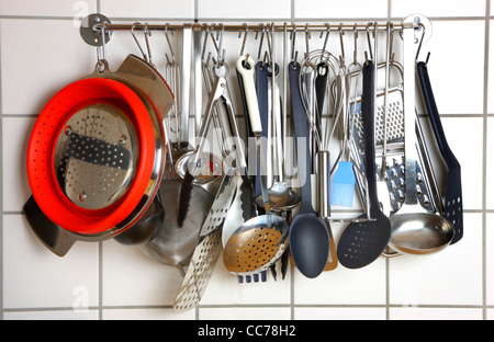 Various kitchen utensils, kitchen tools, hanging at a kitchen wall rack. Stock Photo