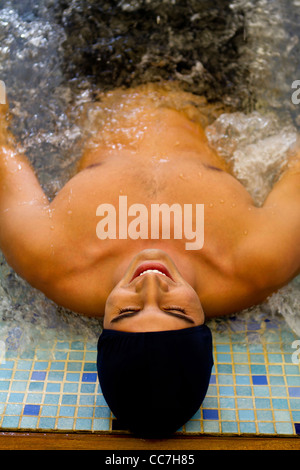 Hispanic man soaking in hot tub Stock Photo