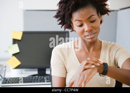 Black businesswoman checking the time at desk Stock Photo