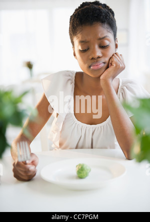 Frustrated Black woman looking at brussels sprout Stock Photo