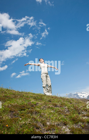 Woman Standing on Mountain Side with Arms Outstretched, Bernese Oberland, Switzerland Stock Photo