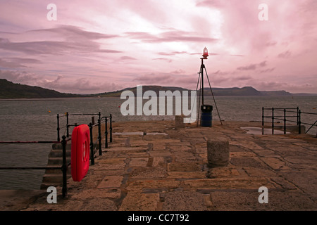 Dawn breaks over the breakwater at the entrance to Lyme Regis harbour, Dorset, England, UK Stock Photo