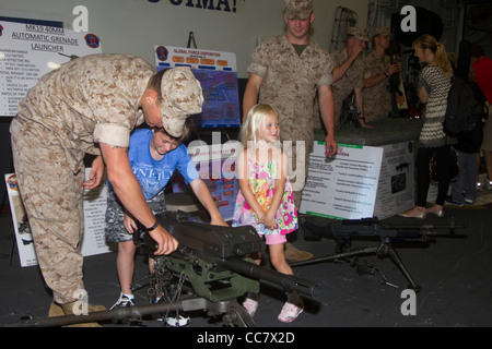 A young boy plays with a machine gun on the USS Iwo Jima while his sister and Marines look on during Fleet Week 2011 in NYC Stock Photo