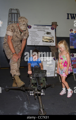 A young boy plays with a machine gun on the USS Iwo Jima while his sister and a Marine look on during Fleet Week 2011 in NYC Stock Photo