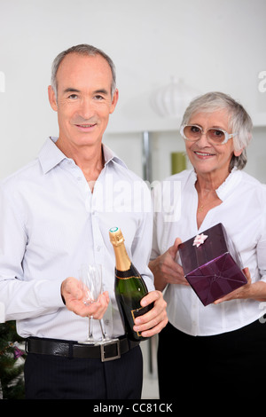 Older couple with champagne and a gift Stock Photo