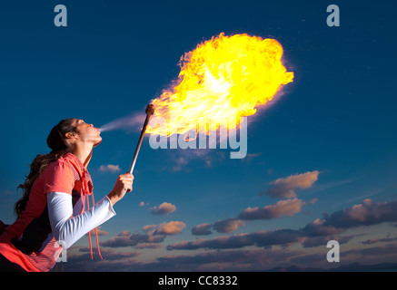 Female fire breather performing at dusk. Stock Photo