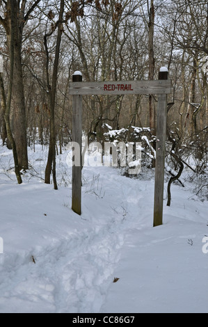 Trail head sign on snow covered path in woods