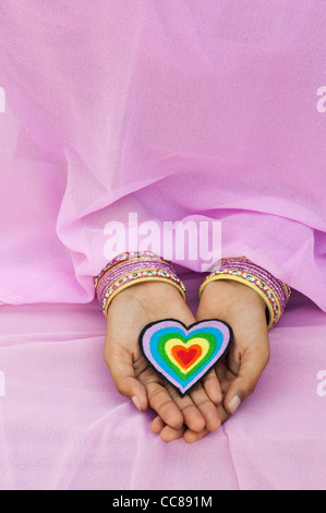 Indian girls hands holding an embroidery iron on patch of a multicoloured love heart Stock Photo