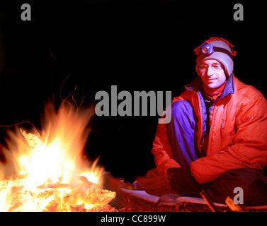 long exposure of a man in cold weather clothing sitting by a campfire Stock Photo