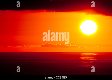 beautiful orange, red sunset over tropical sea reflecting off the ocean with clouds above. Stock Photo