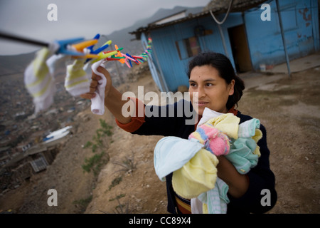 A woman hangs laundry out to dry in a slum in Lima, Peru, South America. Stock Photo