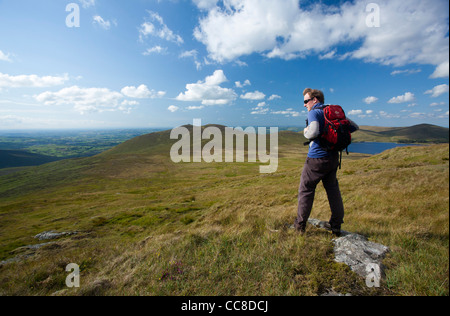 Walker looking across Spelga and the Rocky Valley from Pigeon Rock Mountain, Mourne Mountains, County Down, Northern Ireland. Stock Photo