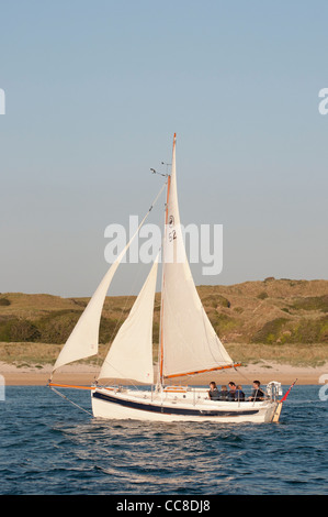 Traditional sailing boat under sail traveling down an estuary Stock Photo