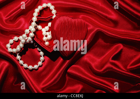 Red heart shape box with necklace on silk background Stock Photo