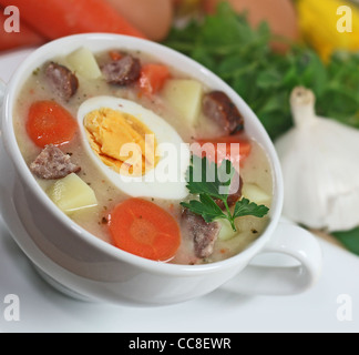 Traditional polish white borscht with eggs and sausage in white dishware for easter Stock Photo