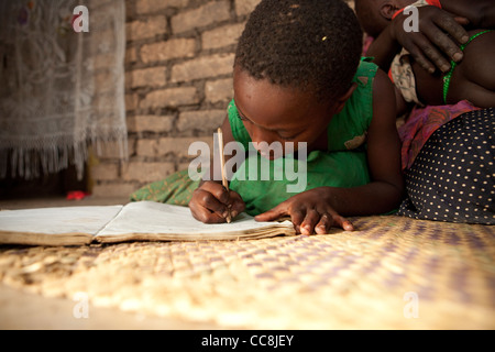 A young girl does school homework inside her house in Maska, Uganda, East Africa. Stock Photo
