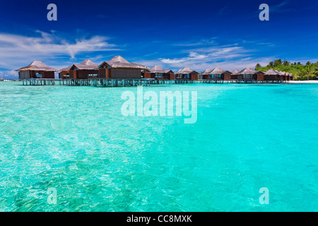 Overwater bungallows in blue lagoon around tropical island Stock Photo