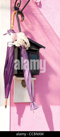 2 parasols and a postbox on a pink painted house in Burano, Italy Stock Photo