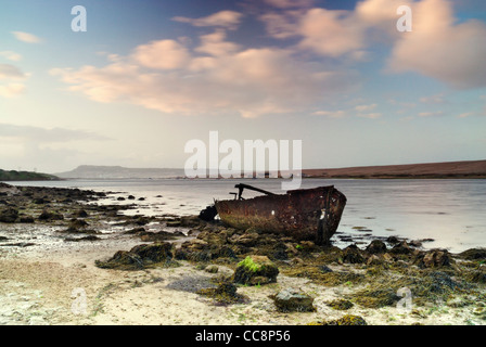 Abandoned rusty boat in Fleet lagoon, Portland and Chesil Beach in the background, weymouth,Dorset,england,uk Stock Photo