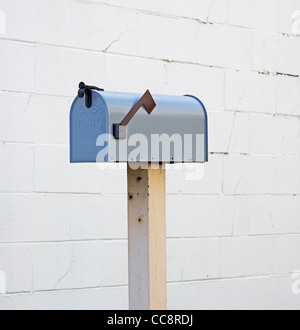 mail box on post next to wall Stock Photo